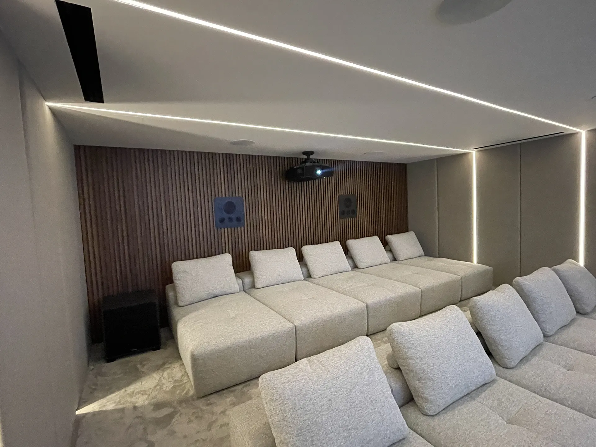 Bodrum Kaplankaya’da İdesis Mühendislik tarafından uygulanan, ahşap çıtalı akustik duvar panelleri ve kumaş kaplamalı modern ev sinema odası tasarımı.